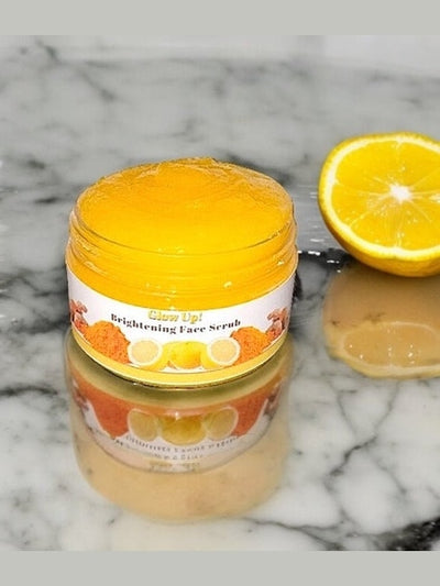 Cozy Up Brightening Face Scrub in a jar with lemon half on a marble surface