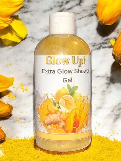 Glow Up Extra Glow Shower Gel in a clear bottle with flowers and turmeric around it