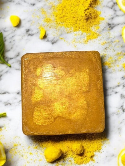Glow Up Gold face soap bar with a shimmering gold finish surrounded by floral and herbal accents