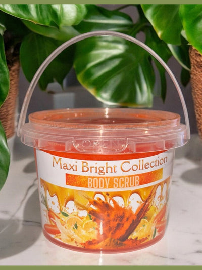 Maxi Bright Collection brightening body scrub in a clear container surrounded by green plants
