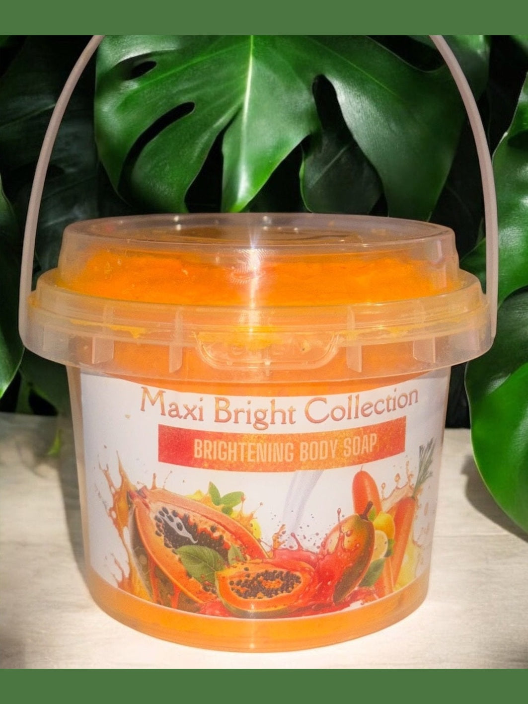Maxi Bright Collection Brightening Body Soap in a clear bucket with vibrant orange color and tropical fruit illustrations
